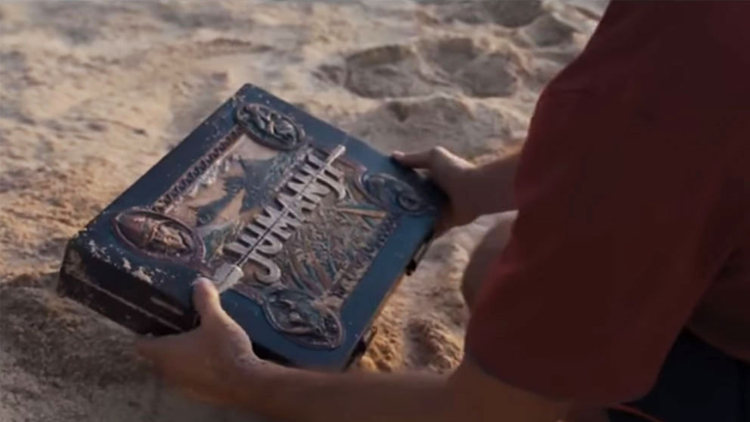 La boîte du jeu Jumanji découvert sur une plage.